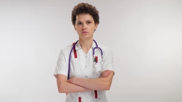 Νεαρός Γιατρός Σταυρώνει Χέρια Κοιτάζοντας Μακριά Ένα Λευκό Φόντο Υψηλής — Αρχείο Βίντεο