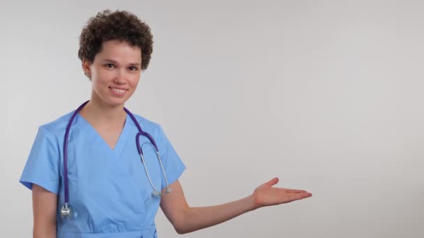 Portret Młodej Lekarki Wskazującej Palcem Prawą Stronę Ramy Białym Tle — Wideo stockowe