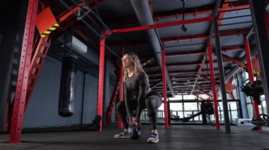  Kadın, kollarının ve omuzlarının kaslarını kettlebell ile eğitir. iki kollu kettlebell salıncak.