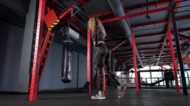  Kadın kalça kaslarını çalıştırır ve sırtında da kettlebell taşır. iki kollu kettlebell salıncak.