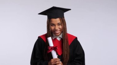 Siyah cüppeli mutlu Afrikalı kız ve usta şapkası diplomasını, öpücüklerini ve sarılmalarını gösteriyor. Yüksek kalite 4k görüntü