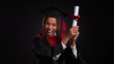 Siyah cüppeli mutlu Afrikalı kız ve usta şapkası diplomasını, öpücüklerini ve sarılmalarını gösteriyor. Yüksek kalite 4k görüntü