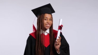 Siyah cüppeli mutlu Afrikalı kız ve usta şapkası diplomasını, öpücüklerini ve sarılmalarını gösteriyor. Yüksek kalite 4k görüntü