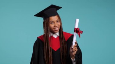 Siyah cüppeli mutlu Afrikalı kız ve usta şapkası diplomasını, öpücüklerini ve sarılmalarını gösteriyor. Yüksek kalite 4k görüntü