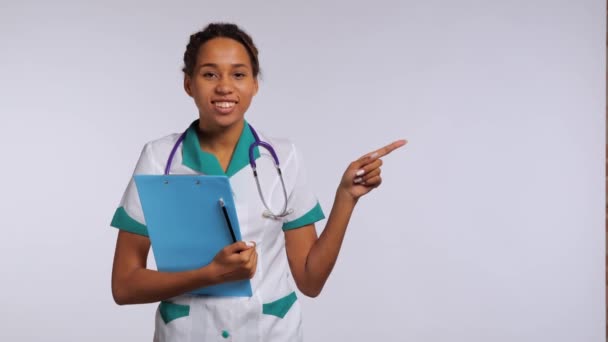 Szczęśliwa Afrykańska Pielęgniarka Mundurze Wskazująca Palcem Prawy Róg Kadru Wysokiej — Wideo stockowe