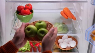 Erkek elleri buzdolabından sebzeli yeşil elma sepeti koyar. Yüksek kalite 4k görüntü