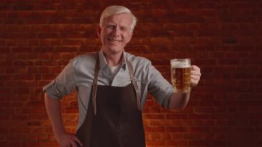 Gri saçlı bira imalatçısı bir bardak taze bira ile poz veriyor. Yüksek kalite 4k görüntü