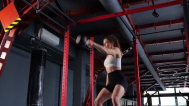  Kadın, kollarının ve omuzlarının kaslarını kettlebell ile eğitir. iki kollu kettlebell salıncak.