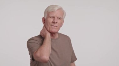 Yaşlı adam boynuna uzanırken huzursuzluk içinde yüzünü buruşturuyor. Çektiği acıya rağmen yüzünde küçük bir gülümseme beliriyor.