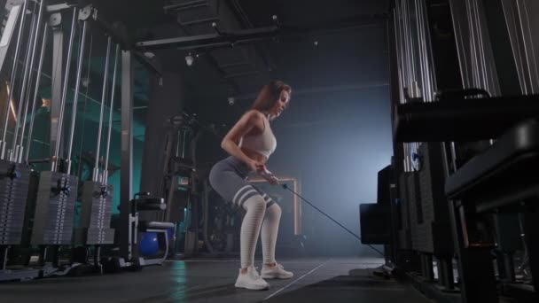 一位女士正在体育馆里用绳子表演蹲姿 用技巧和技巧展示她的大腿肌肉 — 图库视频影像