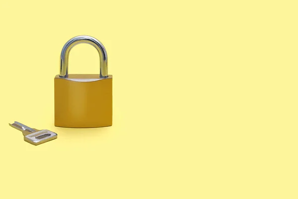 在黄色背景上锁上一个键 并为文本留出空白处 浅黄底色上有银匙的金黄色锁 以锁的形式提供保护和安全的概念 — 图库照片