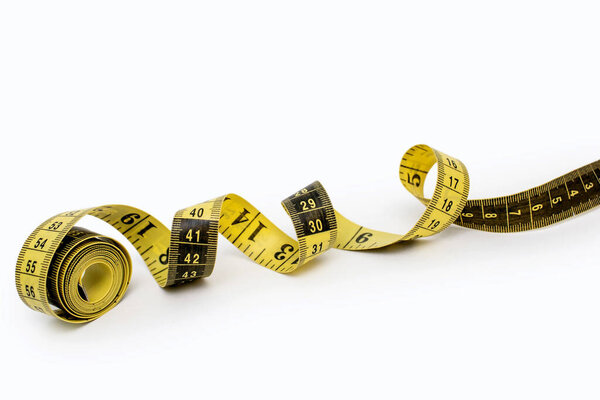 Yellow measuring tape isolated on white background. Tool for measuring length and volume. Yellow-black twisted tape for measuring in the clothing industry or the volume of the human body