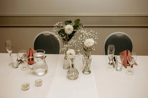 The table for guests in the restaurant is decorated with flowers and candles. Preparation for a banquet and reception of guests in a restaurant. Beautiful table covered with a white tablecloth chairs