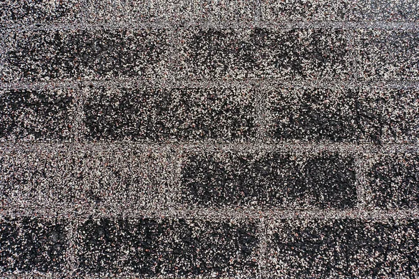 Background from a wall or roof covered with bitumen and gravel close-up. Building material in the form of resin or bitumen to repel moisture. Free space for text