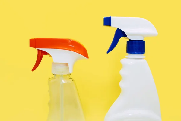 Two plastic cleaning spray bottles on a yellow background. Detergent chemical agent in the form of a spray for cleaning windows, and disinfecting. Concept of house cleaning and cleaning company