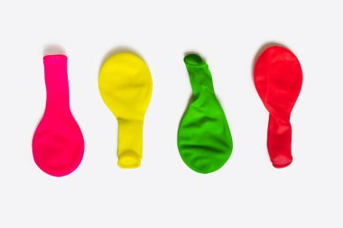 Multi-colored non-inflated balloons on a white background. Balloons for decoration for the holidays in a deflated state. Four airless latex balloons