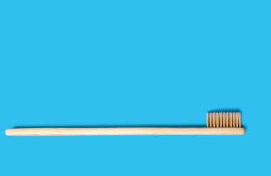 Ecological bamboo toothbrush on a blue background. Wooden toothbrush without plastic. Waste-free personal care products, dental care concept. Free space for text