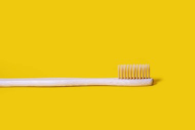 Bamboo toothbrush on a yellow bright background. Eco-friendly plastic-free toothbrush. Free space for text. Waste-free personal care products, dental care concept