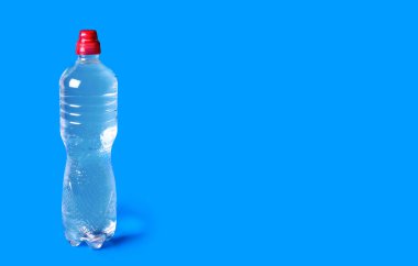 Transparent bottle with clean drinking water on a blue background. Convenient bottle of drinking water. The benefits of clean drinking water for the active life of the human body. Free space for text
