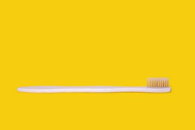 Ecological bamboo toothbrush on a yellow background. Wooden toothbrush without plastic. Waste-free personal care products, dental care concept. Free space for text