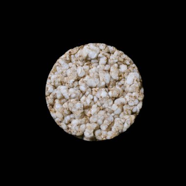 Round rice bread on a black square background close-up. Crispy rice diet product for a healthy lifestyle. Top view puffed rice cake on black isolated background