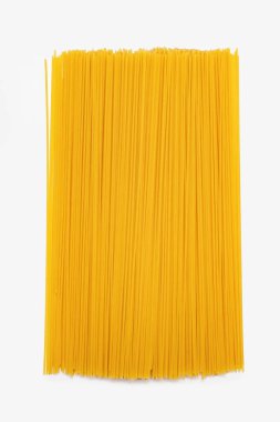 İzole edilmiş beyaz bir arka planda uzun çiğ spagetti. Makarna şeklinde buğdaydan İtalyan mutfağı. Dikey beyaz arkaplanda sarı spagetti.