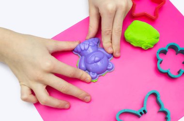 Çocuk yumuşak plastikinle oynar ve bir ayıyı kalıpla şekillendirir. Hava plastiksi yakın plan bir çocuğun elleri ve ayı şeklinde bir kalıp. Modelleme için farklı kalıplar.