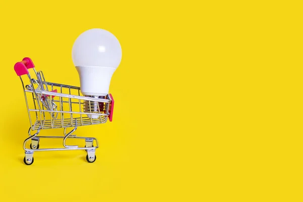 Small Shopping Cart Energy Saving Light Bulb Yellow Background Favorable — Stockfoto
