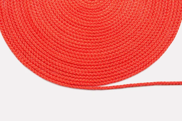 红色的绳子在白色的背景上整齐地扭曲成一个圆圈 红色尼龙绳的纹理紧密相连 红绳卷曲 自由的文字空间 捻得整整齐齐的纺织品绳 — 图库照片