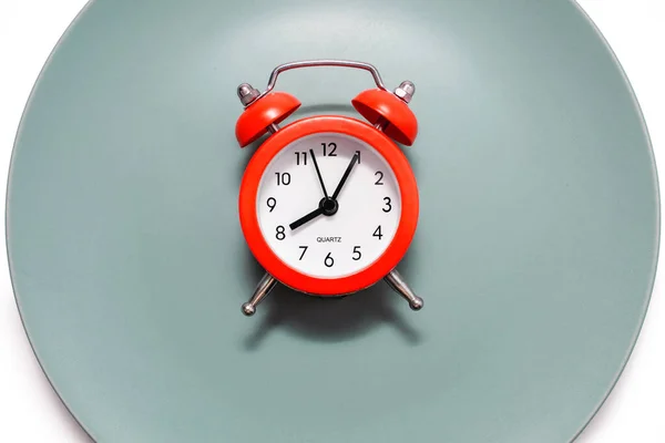 一个红色的闹钟停在白色背景的盘子上 饮食和适当营养的概念在时间表上 午餐休息时间或就餐时间 严格按照约定的时间吃饭 — 图库照片