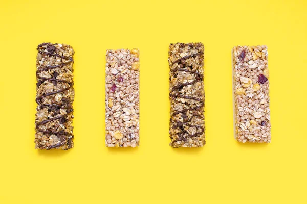 Set of various muesli bars on a yellow background. Delicious and healthy snack in the form of whole grain oatmeal with nuts and chocolate bars with berries. Delicious snack to replenish energy