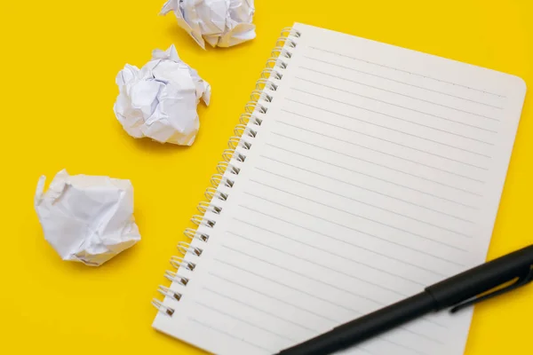 Notebook and pen with crumpled sheets on a yellow background. Notepad with blank sheets and free space for text. Concept of work and business. Write text or work on documents