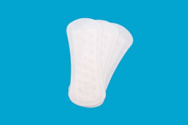 Mavi arka planda pervane şeklinde dizilmiş üç adet adet adet pedi. Kadın hijyen ürünleri hijyenik pedler şeklinde. Temiz adet pedleri kullanmaya hazır.