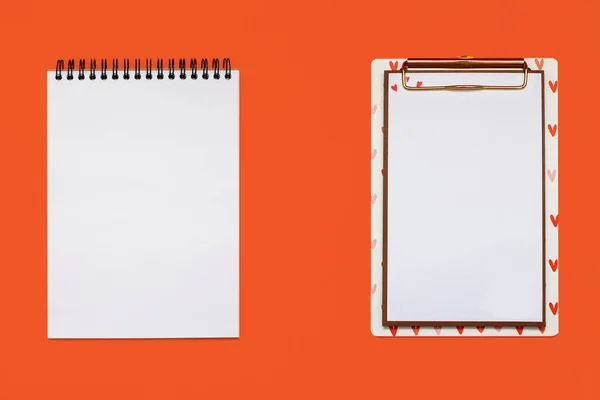 オレンジ色の背景に白い空のシートを持つ2つのノートパッド テキストや図面のための自由なスペースを持つ2つの異なるノートパッド テキストのためのフリースペース — ストック写真