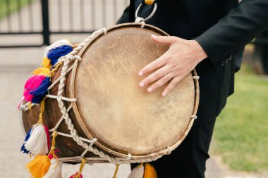 Müzisyenin boynundaki deri davulun yakın çekimi. Davul şeklinde müzik aleti olan bir sokak müzisyeni ritim çalar. Müzikal ritim şeklinde şenlikli müzik eşliğinde.