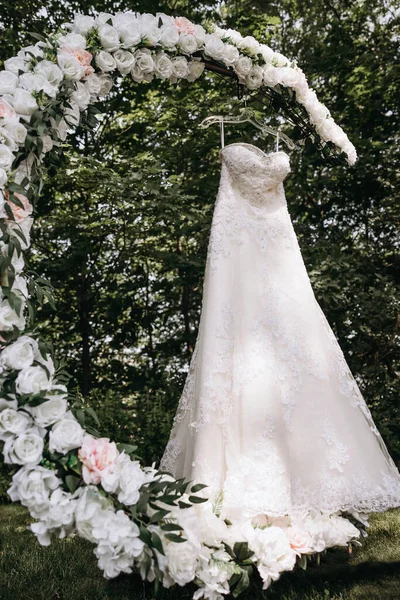 Luxuriöses Hochzeitskleid Hängt Einem Mit Weißen Rosen Geschmückten Hochzeitsbogen Das — Stockfoto