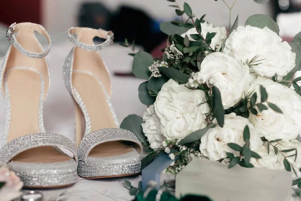 花嫁のハイヒールの靴とバラの結婚式の花束を閉じます 靴の形で結婚式のアクセサリーや儀式のための花束 花嫁の輝く靴と豪華な花束 — ストック写真