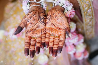 Hintli bir gelinin elleri, geleneksel Hint tarzında kınalar ve desenlerle süslenmiştir. Gelinin elinde Hint tarzı mehendi üst görünümü var.