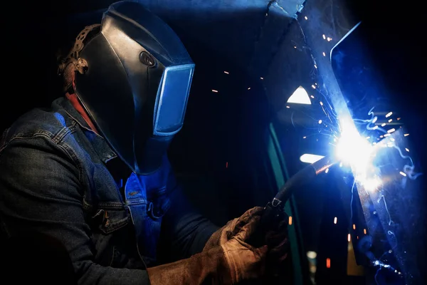 焊机使用焊接设备工作 用金属制造焊缝 焊工戴着防护面罩和手套 使用焊接设备时的火花和火灾 — 图库照片