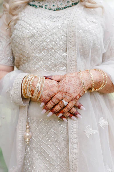 Indian bride\'s hands are decorated with Indian style henna bracelets and patterns. Hands of the bride close-up with patterns and ornaments in traditional Indian style. Beautiful Indian bride dress