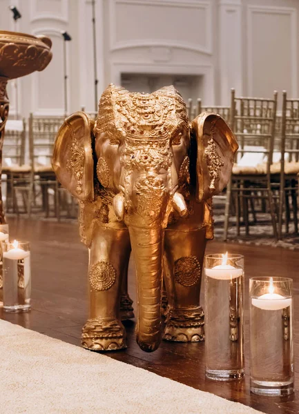 Decor in the Indian style in the form of a golden elephant and candles. Elephant of Ganesha in the form of decor in a restaurant. Indian traditional culture