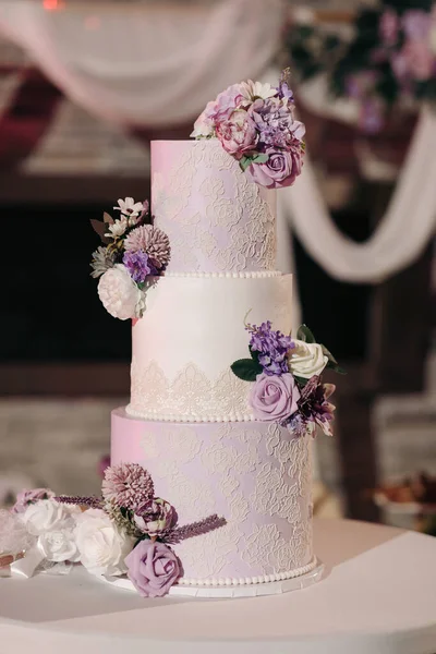 A beautiful tiered cake decorated with flowers at a wedding party. Delicious chic wedding cake in a restaurant for guests of the bride and groom
