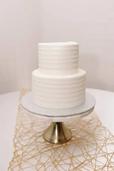 Two-tier wedding cake with white cream, undecorated. White cake on a plate on a white background. Festive two-tier cake with white cream without decoration