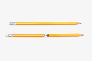 Beyaz yatay arka planda kırık ve bütün bir kalem. İki sarı grafit kalem kırılmış ve yakından çekilmiş. Duygular, stres, öfke, çalışmada sorunlar, işte sorunlar. Konsepti durdur