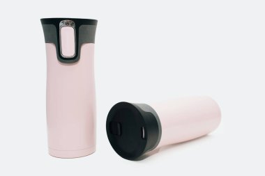 İki tane pembe su şişesi beyaz arka planda duruyor ve yatıyor. Çay, kahve ya da su için modern pembe termos. Sıcak içecekler, seyahat şişesi, yeniden kullanılabilir su şişesi için seyahat termosu..