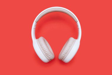 Turuncu arka planda tek beyaz kablosuz bluetooth kulaklık. Oyun oynamak ve müzik dinlemek için kulaklıktan kablosuz kulaklık. Müzik konsepti.