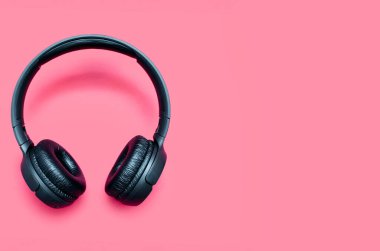 Siyah renkli kablosuz kulaklıklar kırmızı arkaplanda izole edilmiş ve metin için boşluk var. Oyun oynamak ve müzik dinlemek için yakın çekim yolu ile yakın plan kablosuz bluetooth kulaklıklar