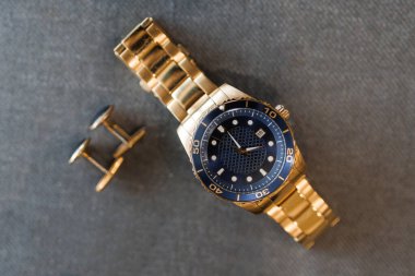 Gri arka planda kol düğmeleri ve çevirmeli erkek mekanik saati. Klasik erkek aksesuarları. Dakiklik ve iş konsepti