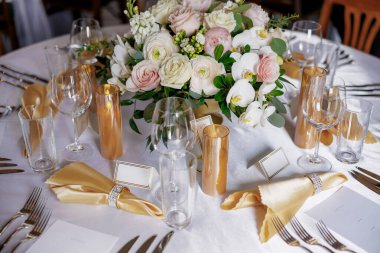 Masa düzenleri ve çiçeklerle süslenmiş güzel bir masa. Bir restoranda lüks bir şekilde dekore edilmiş bir masa. Gümüş çatal bıçak, çiçekler ve temiz bardaklar restorandaki masayı süslüyor.