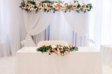 Gelin ve damadın masası bir restoranda çiçekler ve mumlarla süslenmiş. Güller, gelin ve damadın sofrasını şenlikli bir ziyafetle süslüyor.